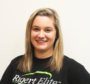 A woman in black shirt standing next to wall.