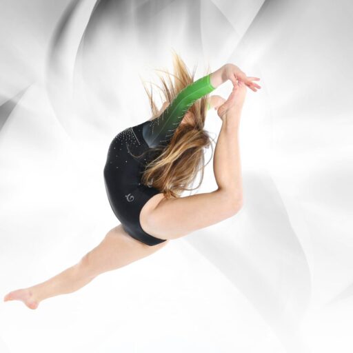A female gymnast in mid-air performing a dynamic dance maneuver, dressed in a black leotard, against a white background.