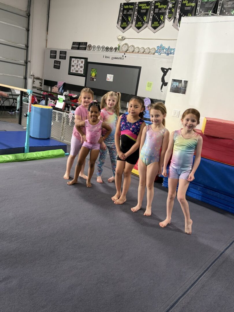 Six young gymnasts posing on mat