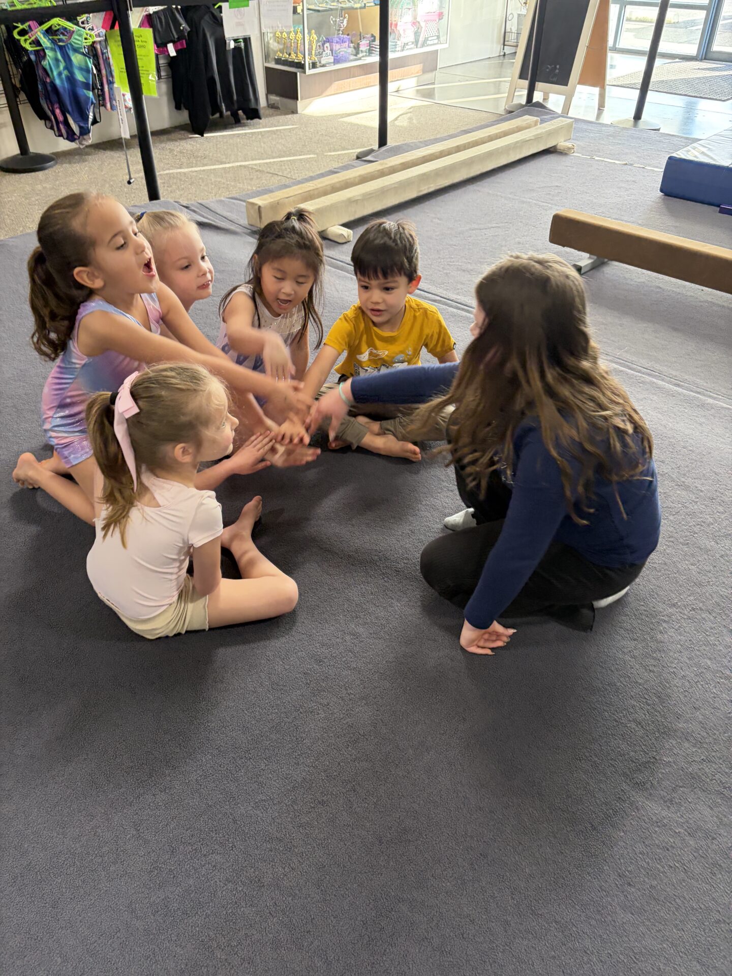 Children joining hands in gymnastics class circle