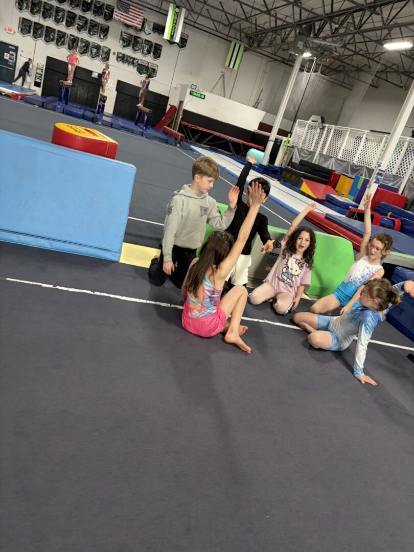 Kids in gymnastics class stretching on mat